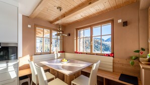 A modern kitchen with a wooden table, white chairs, and a built-in bench.