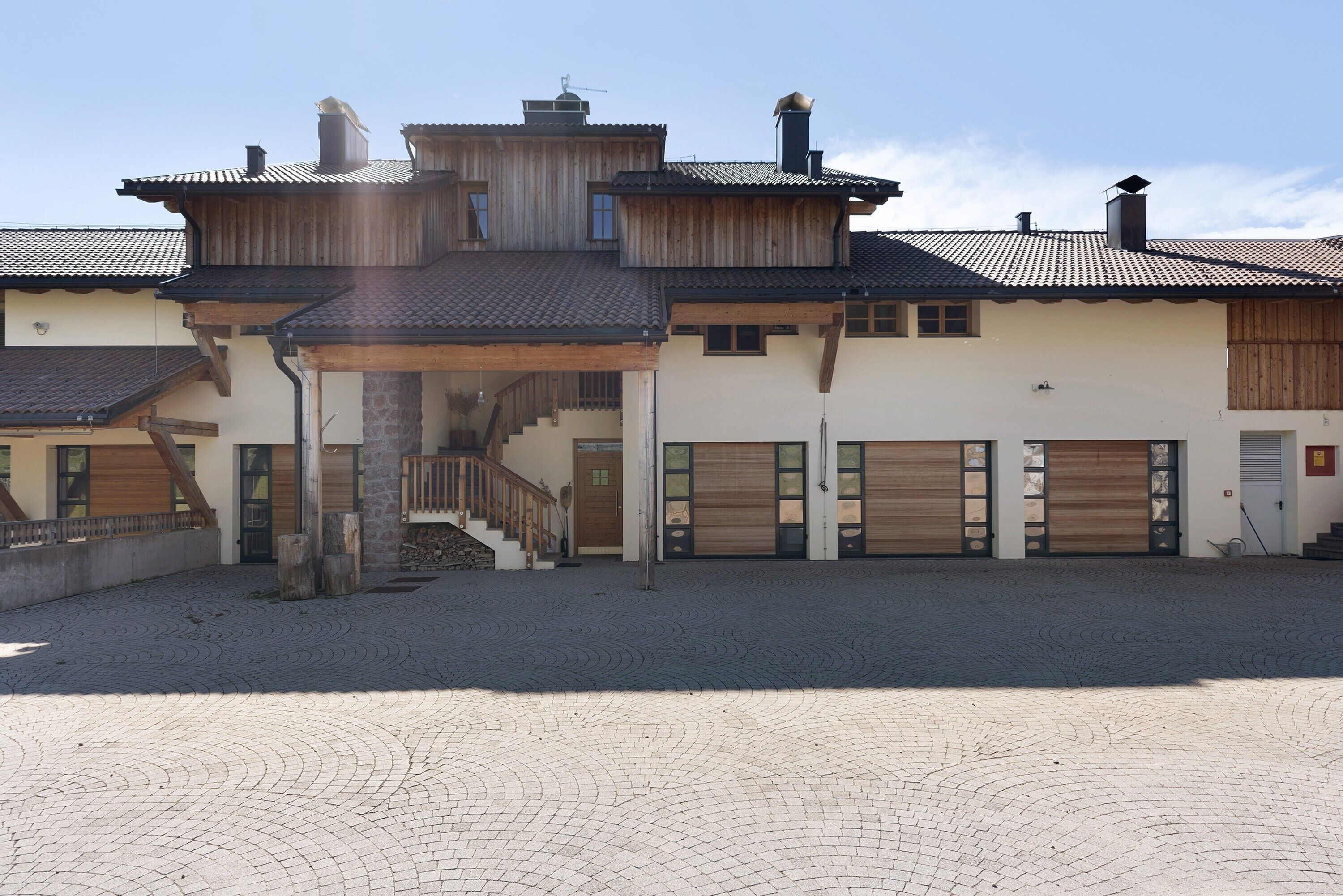 A two-story building with a covered entrance, a staircase, and a paved courtyard.