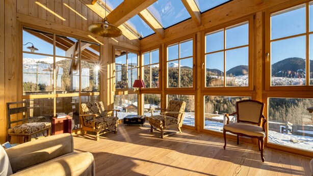 A spacious room with large windows, wooden beams, and multiple seating areas.