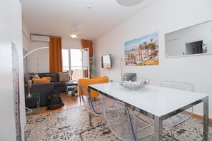 Un salon moderne avec un canapé, une table à manger et un téléviseur.