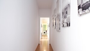 Un estrecho pasillo con suelo de madera, paredes blancas y fotografías del paisaje urbano.
