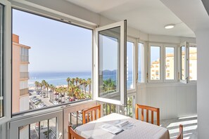 Un balcon avec une table, des chaises et une vue sur la plage et l’océan.