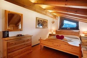 A wooden bedroom with a bed, dresser, and a large mirror.