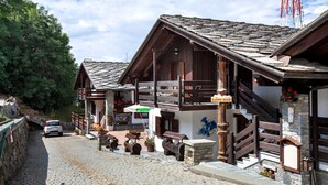 A traditional wooden building with a stone facade, a balcony, and a sign indicating a restaurant. - Apartment 'Elois' with Mountain View, Shared Terrace and Wi-Fi (Gressan)