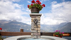 A stone fountain with a sign indicating 'RECEPTION' and a wooden railing. - Apartment 'Sylvie' with Mountain View, Shared Terrace and Wi-Fi (Gressan)