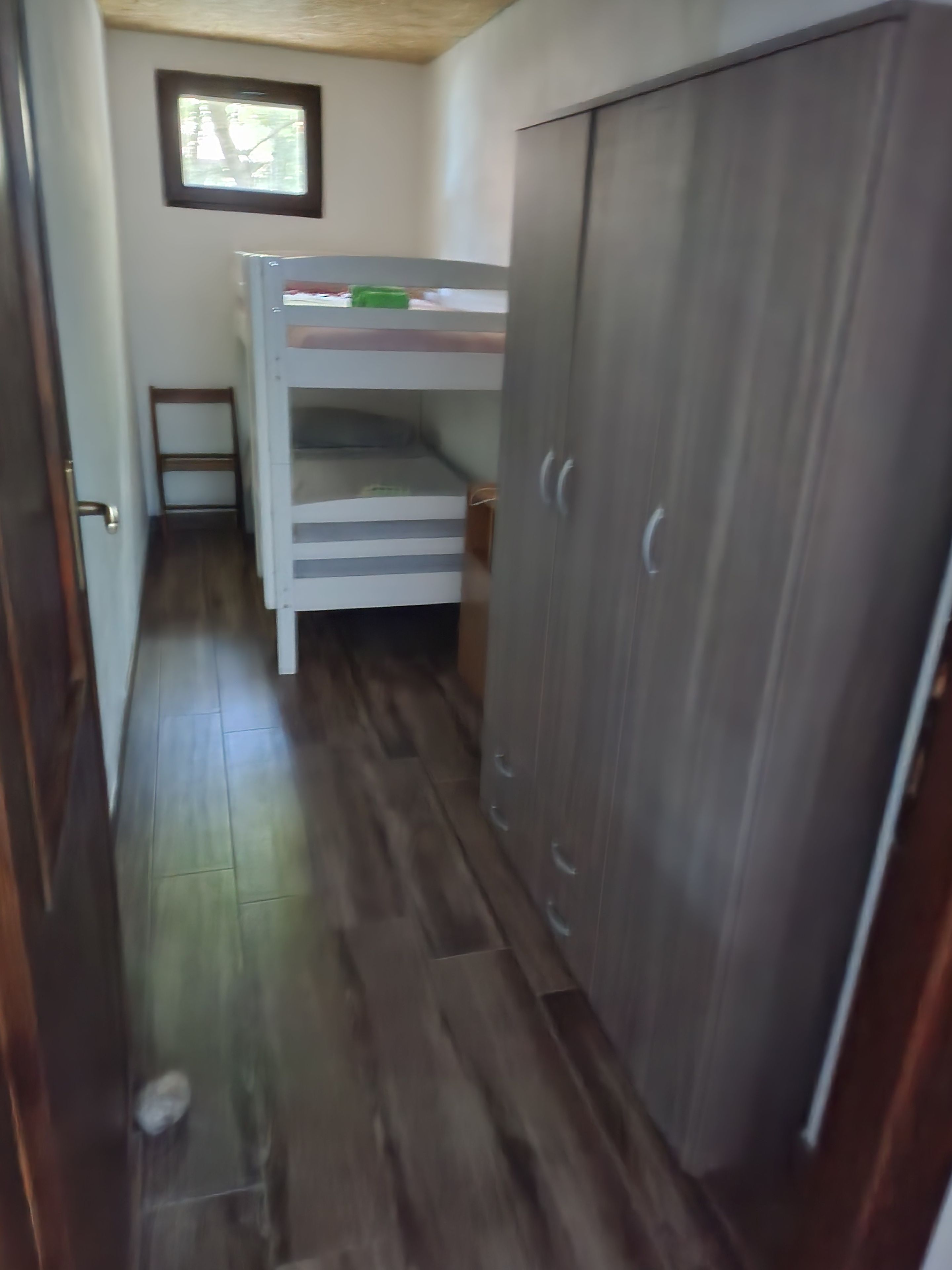 Un pasillo estrecho con una cama litera y un armario.