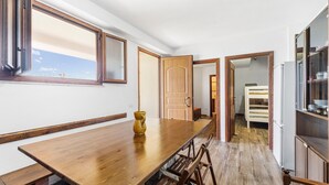 A long wooden dining table with chairs, a vase, and a view through a window. - Aventino Gutturu Holiday Home with Sea View, Private Terrace and Garden (Gutturu)