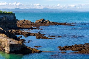A coastal landscape with rocky terrain and a clear view of the sea.