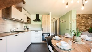 Une cuisine moderne avec des armoires blanches, un comptoir en bois et un coin repas comprenant une table en bois mise pour quatre personnes.