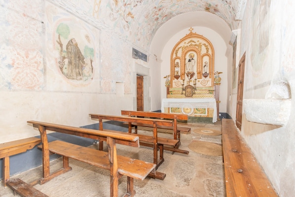 Un intérieur avec des bancs en bois, un sol en pierre et un iconostase religieux.