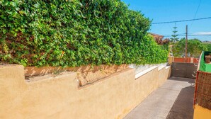 A narrow alleyway with a concrete wall on one side and a hedge on the other. - Holiday Home 'Villa Sunset' with Sea Views, Wi-Fi and Air Conditioning (Calafell)