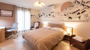 A bedroom with a bed, a desk, a chair, a wall-mounted air conditioner, and a wall mural. - Zen House in the Pyrenees, Private Terrace and Wi-Fi (Coarraze)
