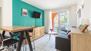 Una cucina moderna con una parete verde acqua, un'area pranzo con tavolo e sedie in legno, e un divano con cuscini colorati.