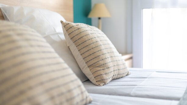 Un letto rifatto con cuscini a righe e un cuscino bianco semplice.