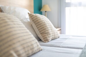 A neatly made bed with striped pillows and a plain white pillow. - Apartment 'Meu Delit' with Shared Pool, Private Terrace and Private Garden (Cerbère)