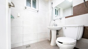 Ein Badezimmer mit weißen Fliesen, einem Waschbecken, einer Toilette und einer Dusche.
