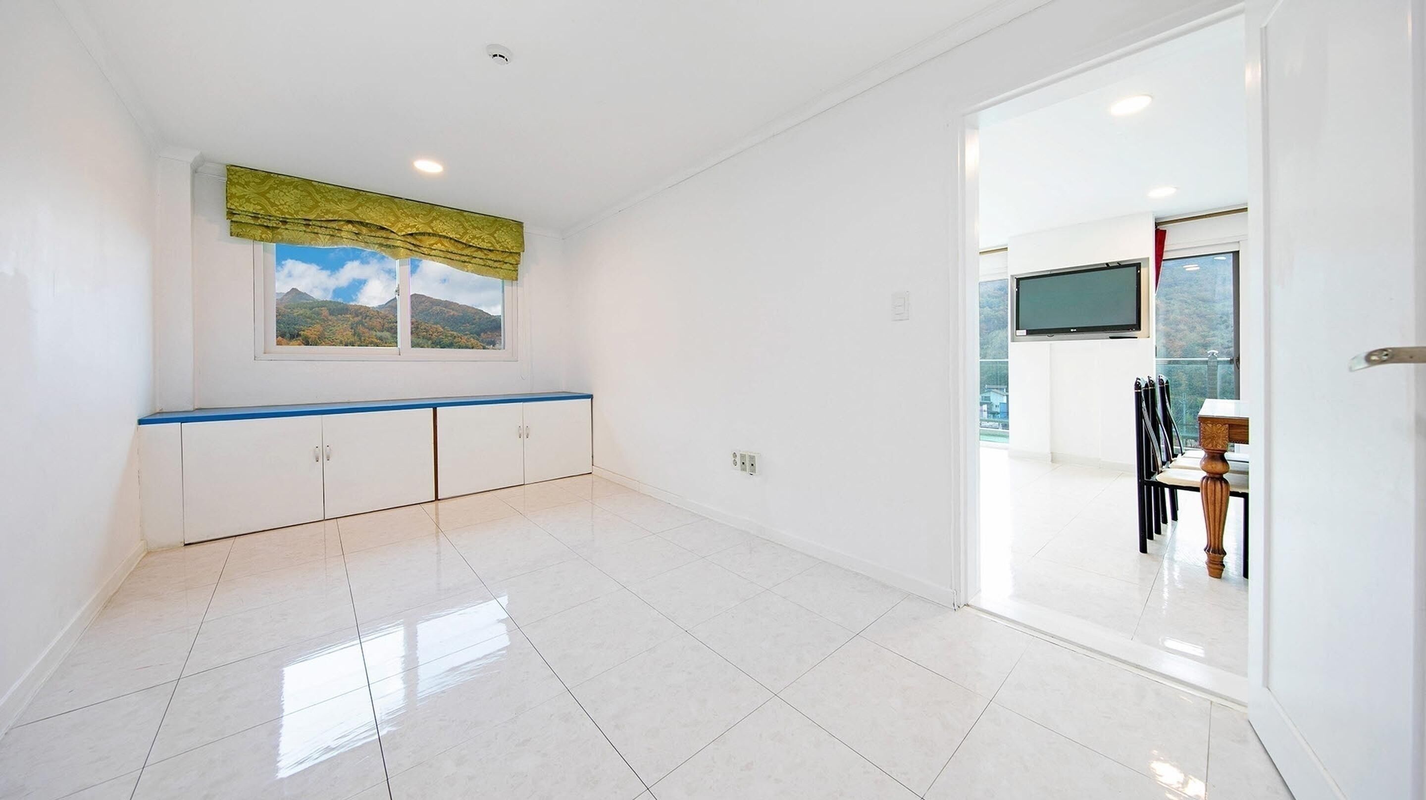 A spacious room with a large window, a blue countertop, and a view of mountains.