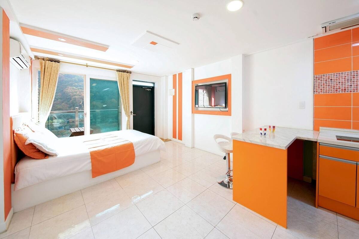 Een moderne hotelkamer met een bed, een klein bureau en een kitchenette.