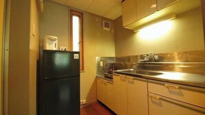 Eine kleine Küche mit Kühlschrank, Spüle und Holzschränken.