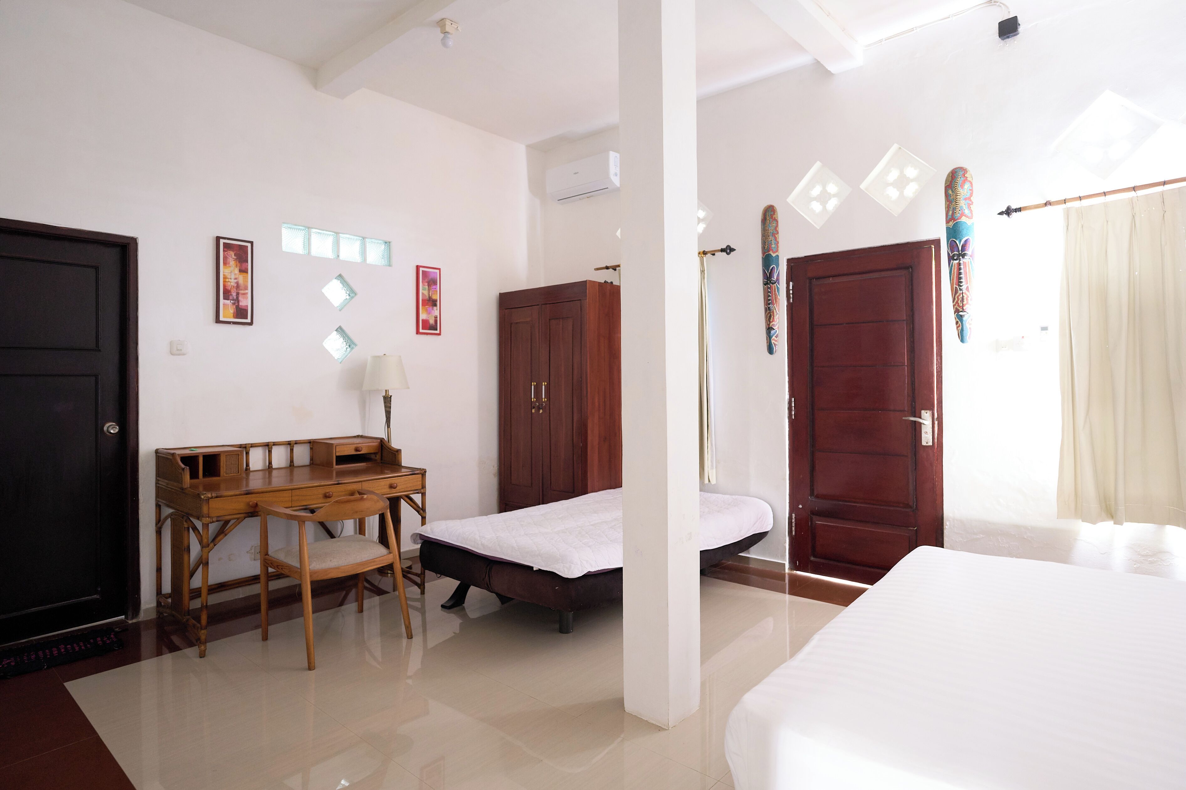 A room with a bed, a desk, a chair, a wardrobe, and a door.