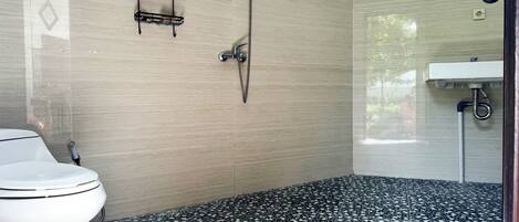 A bathroom with a toilet, a shower, and a sink.