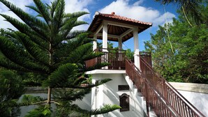 A white building with a red-tiled roof and a wooden balcony. - Seva Hotel (Karangasem)