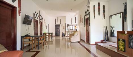 A spacious living area with a dining table and chairs, a sofa, and a reception desk with a Buddha statue.