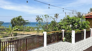 A balcony with a view of the ocean, a tiled floor, and a railing. - Seva Hotel (Karangasem)