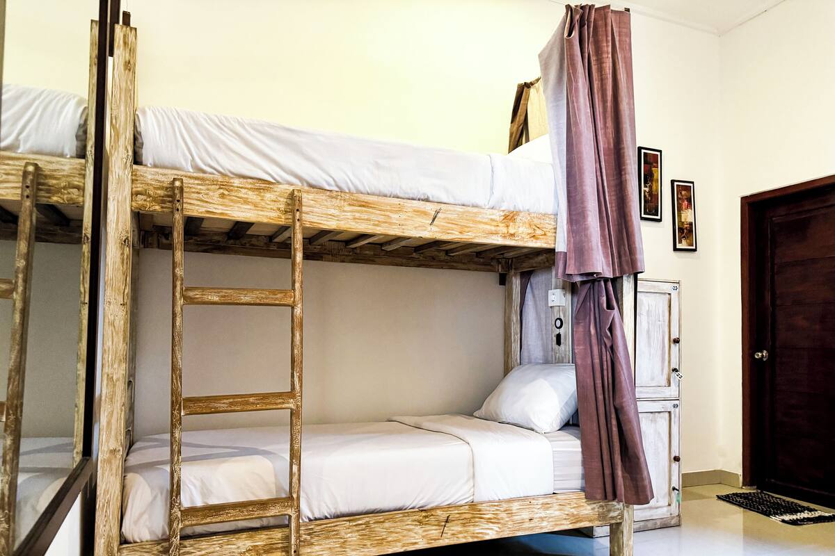 Ein Stockbett mit einer Leiter, weißer Bettwäsche und einer Tür mit einer Nummer.