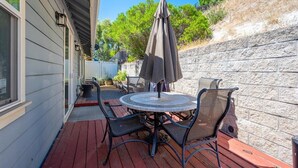 Une terrasse extérieure avec une table ronde et des chaises, un parasol et un muret en pierre.