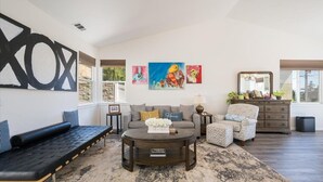 Un salon avec un canapé, une table basse et des œuvres d’art accrochées au mur.