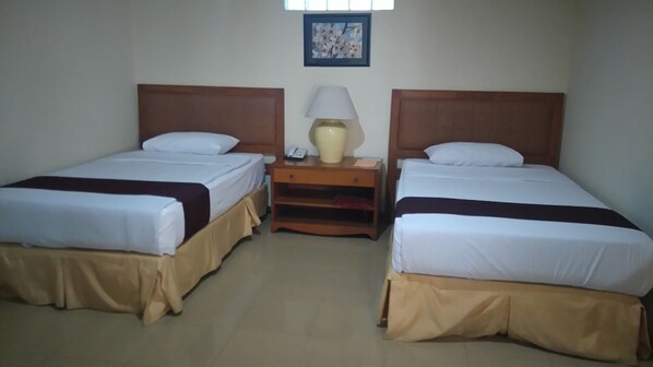A hotel room with two single beds, a nightstand with a lamp, and a framed picture on the wall. - Resort Prima Cipayung (Megamendung)