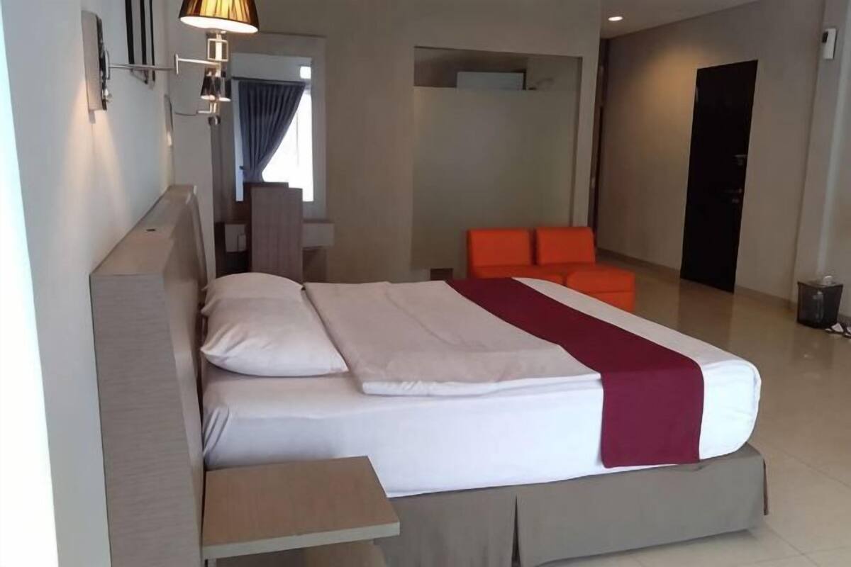 A hotel room with a bed, a nightstand, a chair, and a desk.