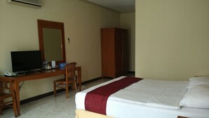 Una habitación de hotel con una cama, un escritorio con una silla, un televisor y un armario.