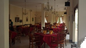Un comedor con varias mesas y sillas, candelabros y una persona al fondo.
