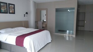 Una habitación de hotel moderna con una cama grande, un tocador con espejo y una ducha a ras de suelo.