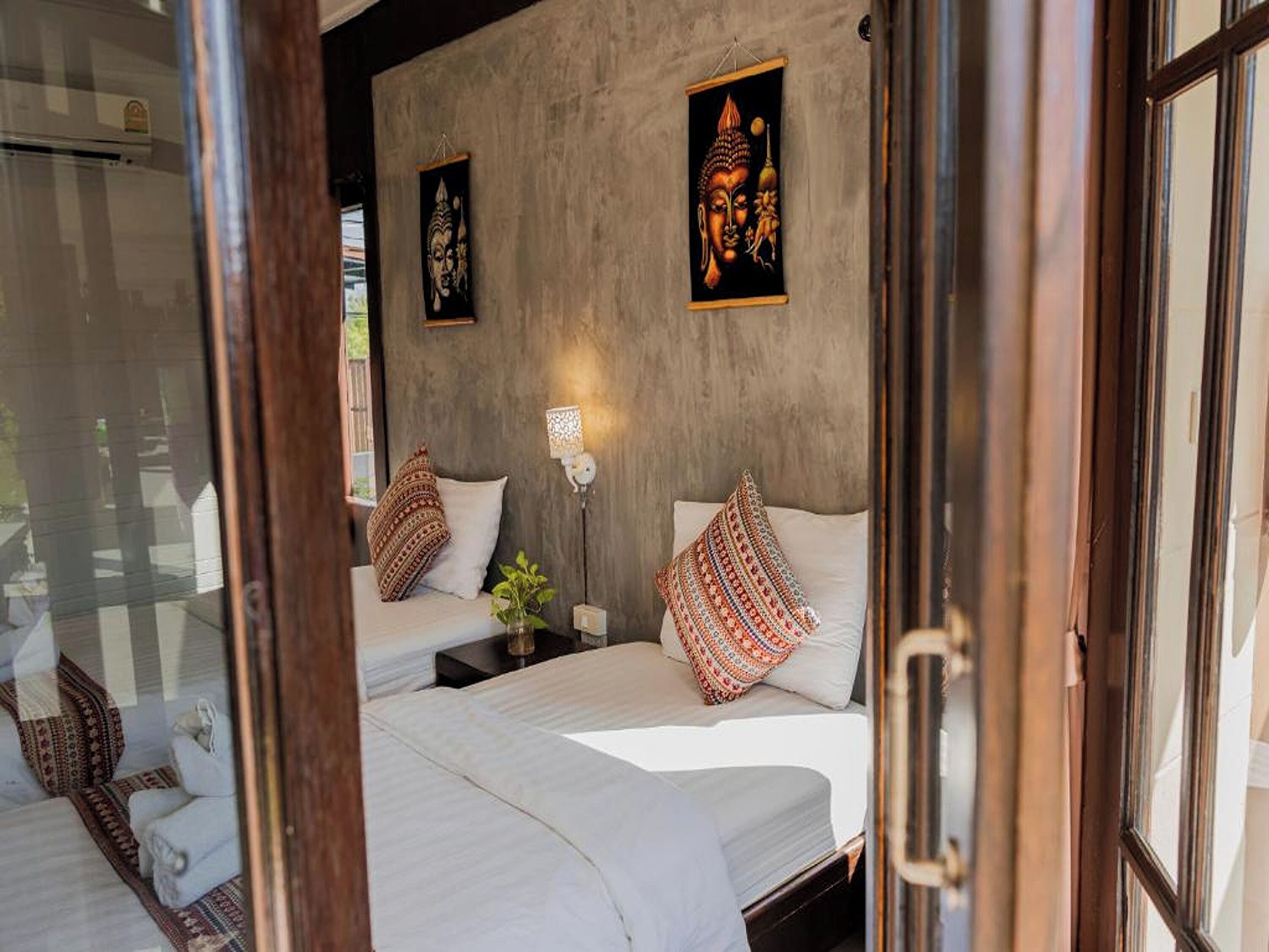 A room with two beds, a window, and two wall-mounted lamps.