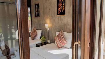A room with two beds, a window, and two wall-mounted lamps.