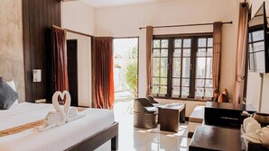 A hotel room with a bed, a desk, a chair, and a large window.