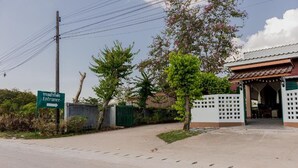 A gated entrance with a sign, a building with a tiled roof, and a clear sky.