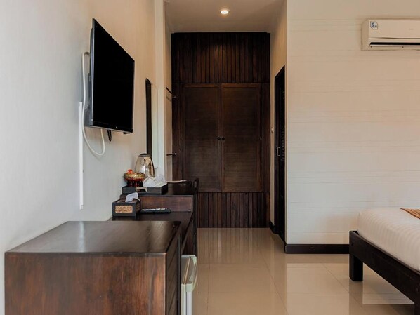 Habitación de hotel con escritorio de madera, televisor de pantalla plana, armario y cama.