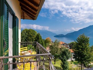 Un balcon avec une table et des chaises jaunes, donnant sur un lac et des montagnes.