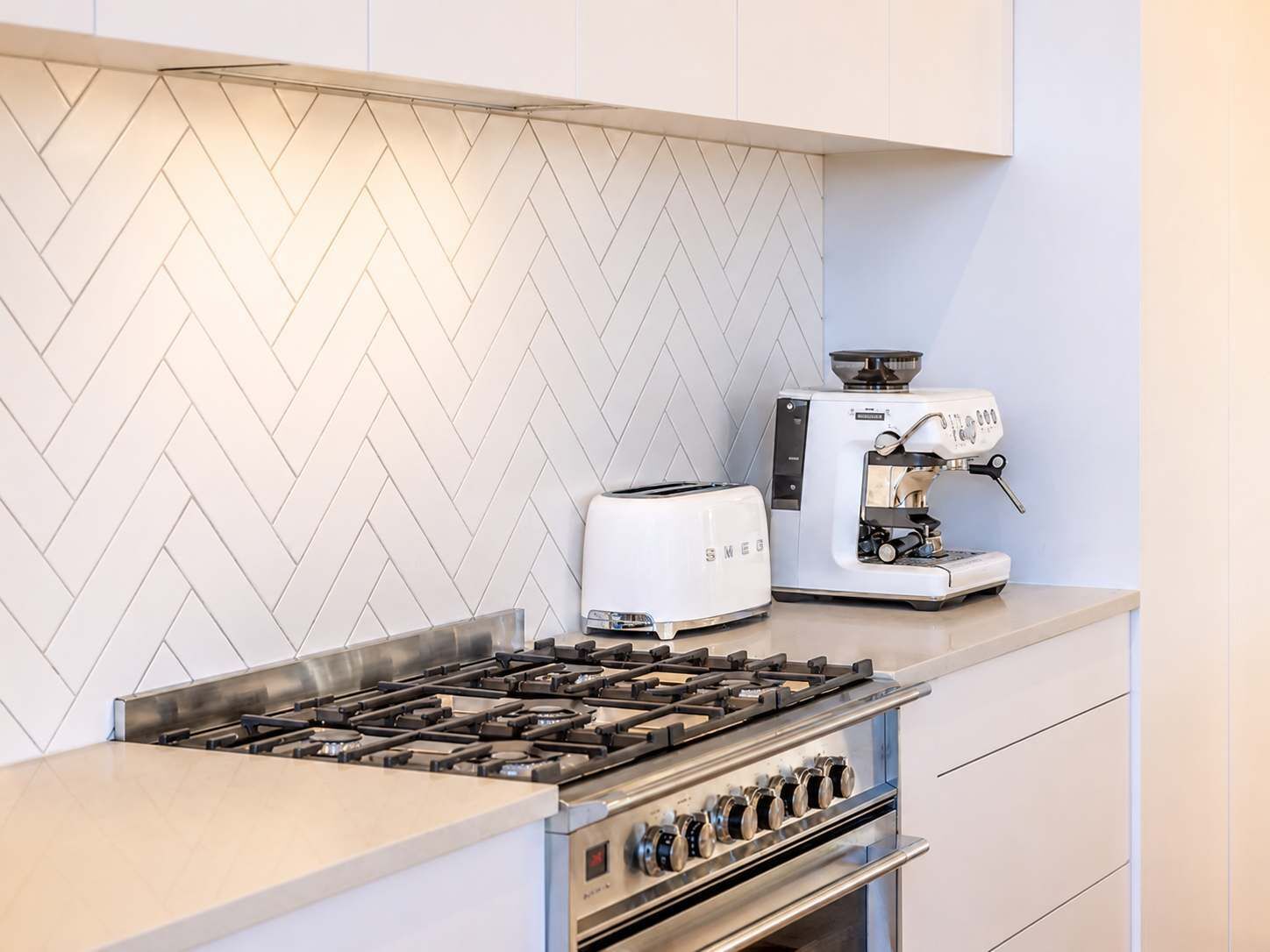 A kitchen with a gas stove, a toaster, and a coffee machine.