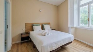 A bedroom with a bed, bedside tables, a window, and a door. - Setúbal Prime IV, Apartment (Setúbal)