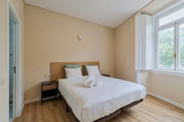 A bedroom with a bed, bedside tables, a window, and a door. - Setúbal Prime IV, Apartment (Setúbal)