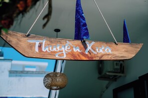 Een houten bordje met de tekst 'Thujen Xua' dat aan het plafond hangt.
