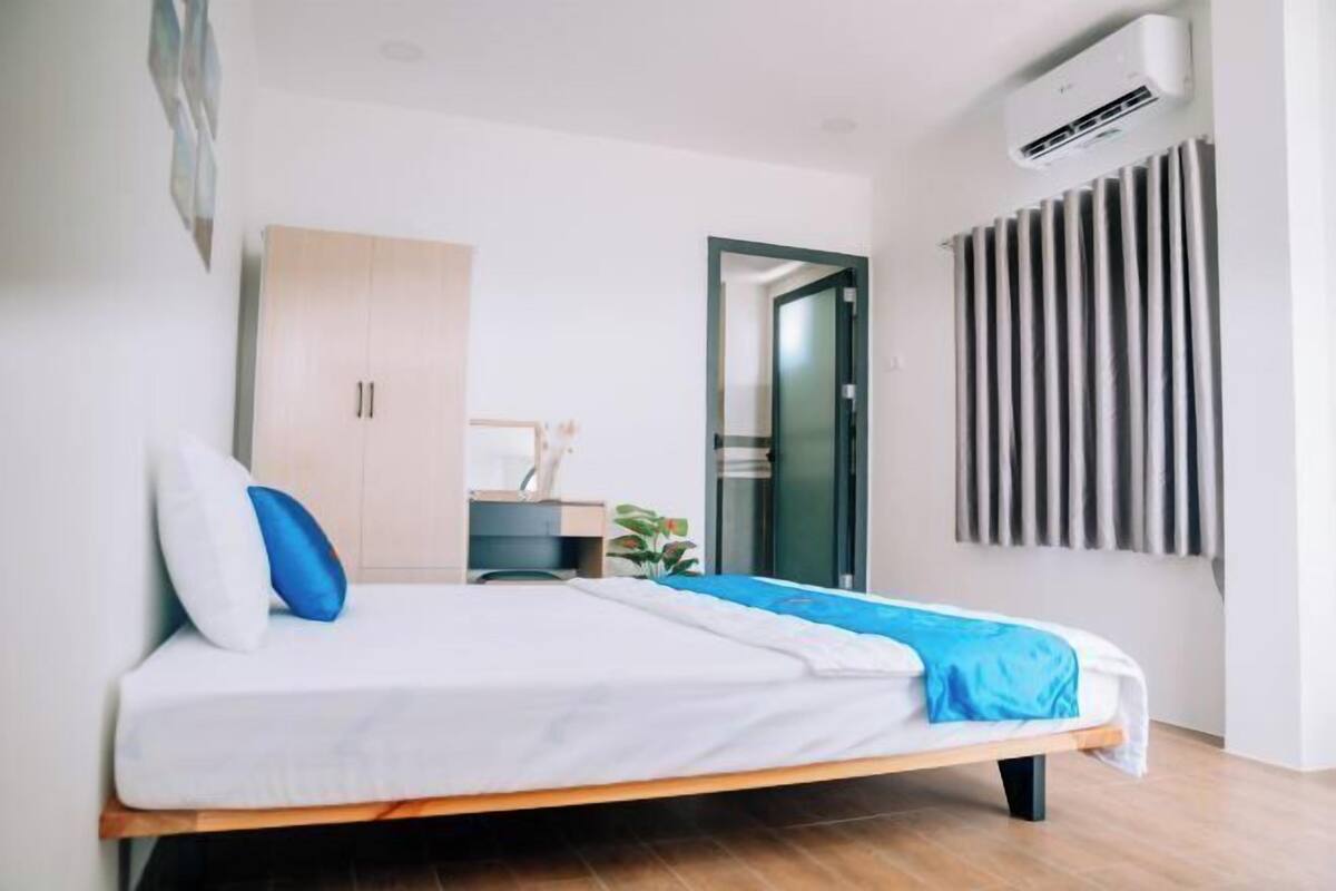 Un dormitorio moderno con cama, armario, escritorio y equipo de aire acondicionado.