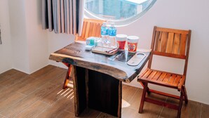 A room with a round window, a wooden table with a chair, and a curtain. - Thuyen Xua Homestay Phu Quy Island (Phu Quy)