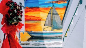 A narrow corridor with artificial green carpet, a sailboat mural on the wall, and a large red floral arrangement on the left. - Thuyen Xua Homestay Phu Quy Island (Phu Quy)
