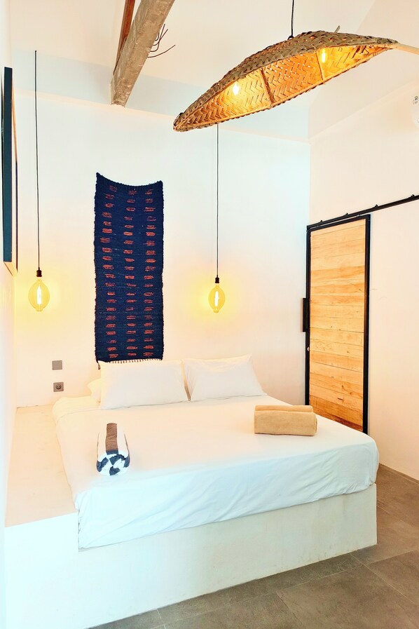 A modern bedroom with a bed, hanging light fixtures, and a wooden wardrobe. - Corner House (Canggu)